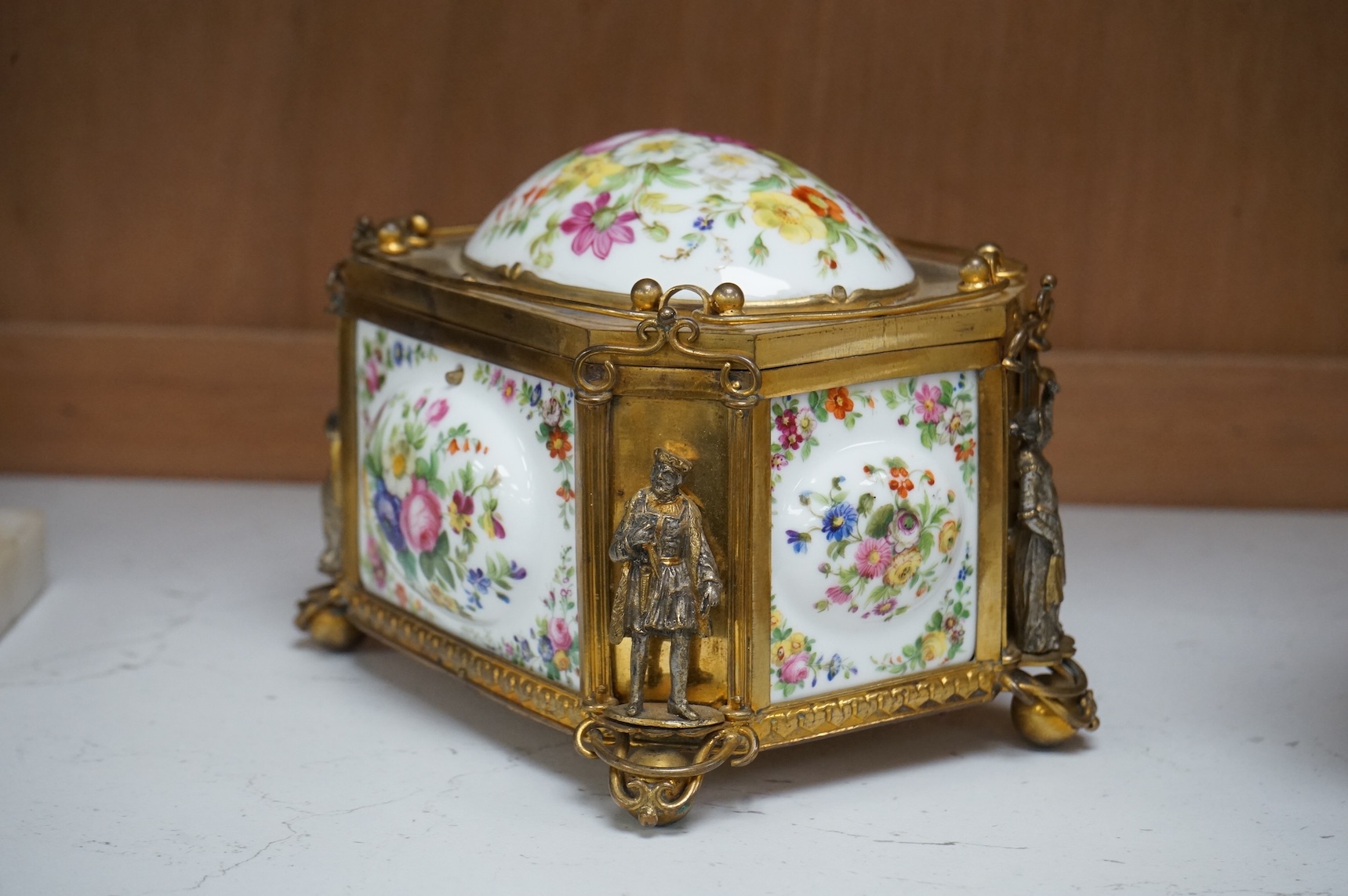 A gilt-brass figural and floral porcelain jewellery casket, 14cm wide, 11cm high.